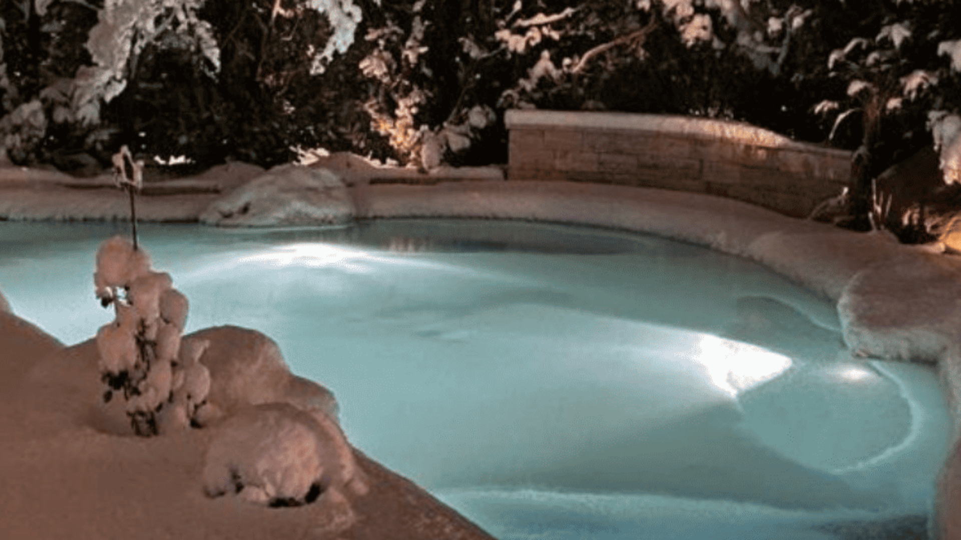 Verschneiter BIO.design Pool im Winter und beleuchtet